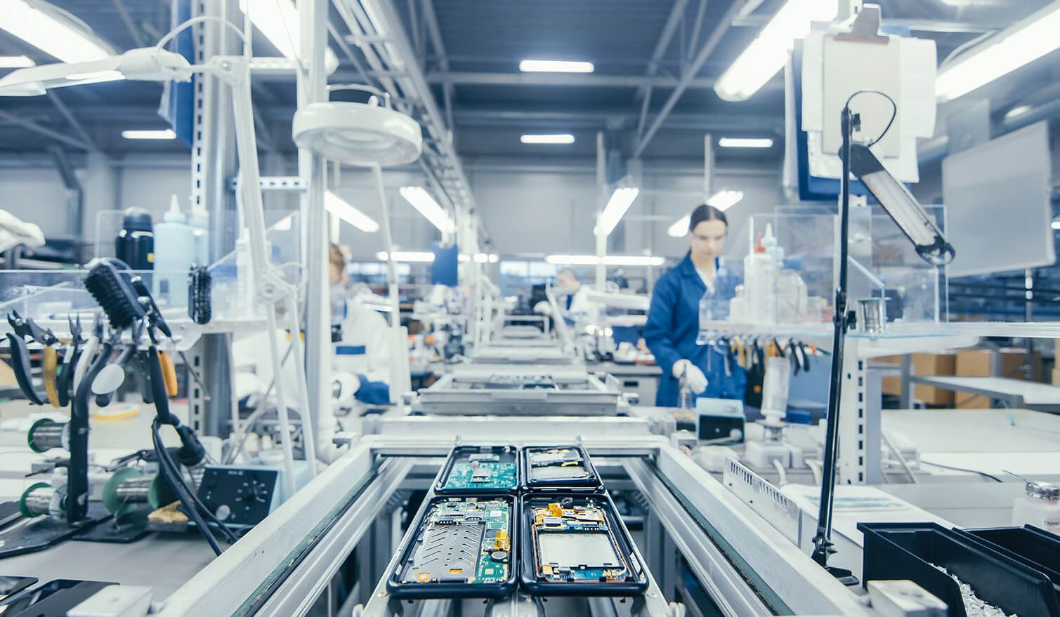 Workers in a production facility, assembling electronic components under specially designed lighting