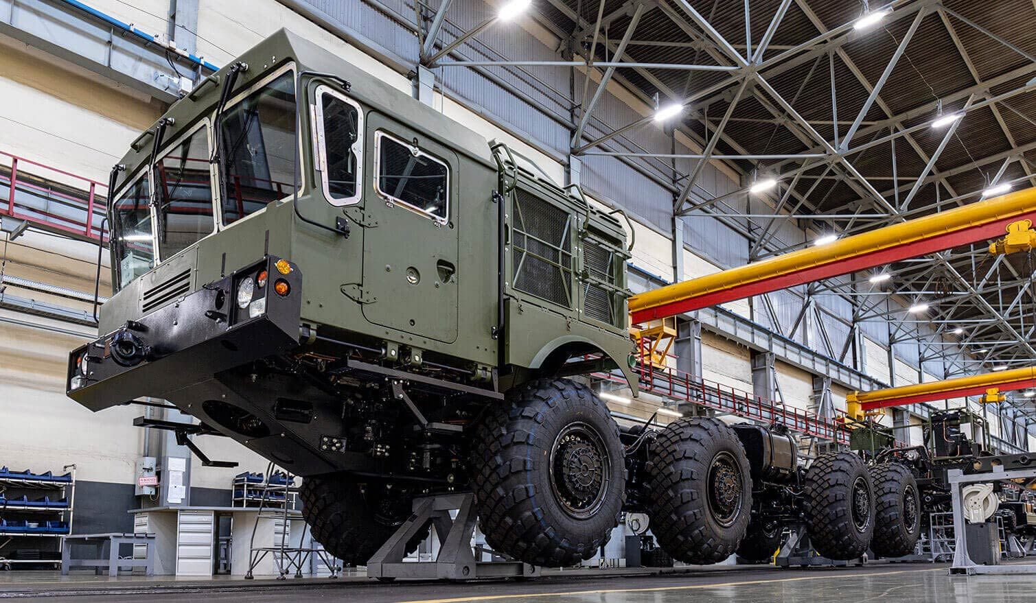 Workers in the factory are building a large military vehicle in a well-lit and well-organised workplace