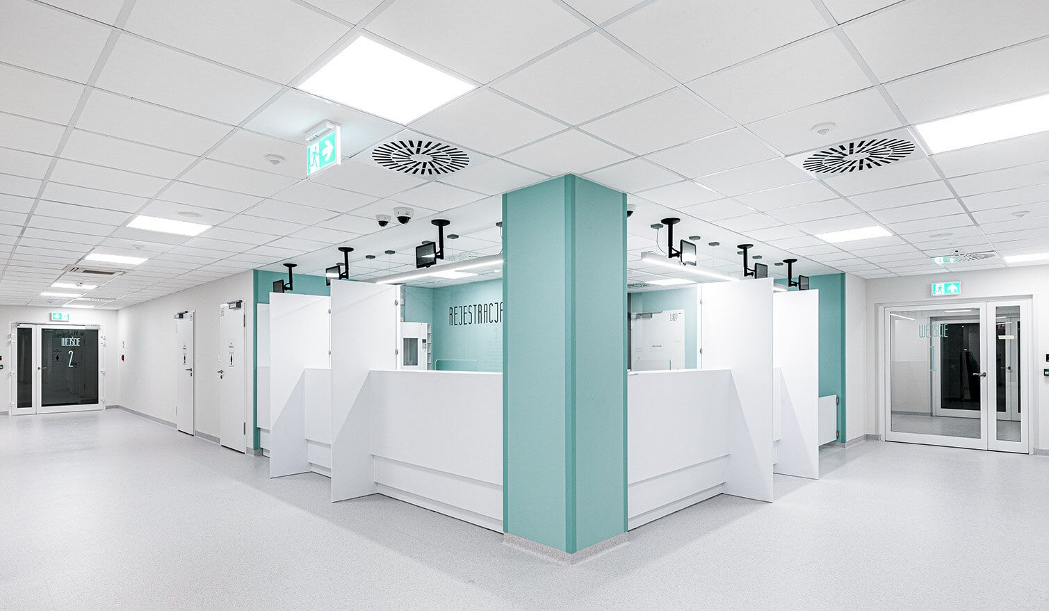 A hospital corridor with a white ceiling and blue walls, creating a welcoming and safe environment for patients. | Lumedic