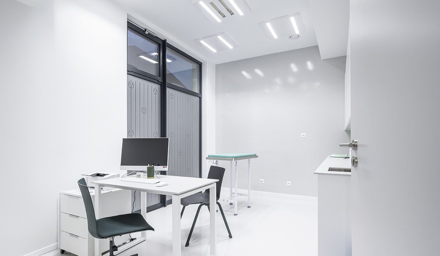 A bright interior of a doctor’s surgery with a desk and a computer, providing suitable conditions for medical consultations | Lumedic