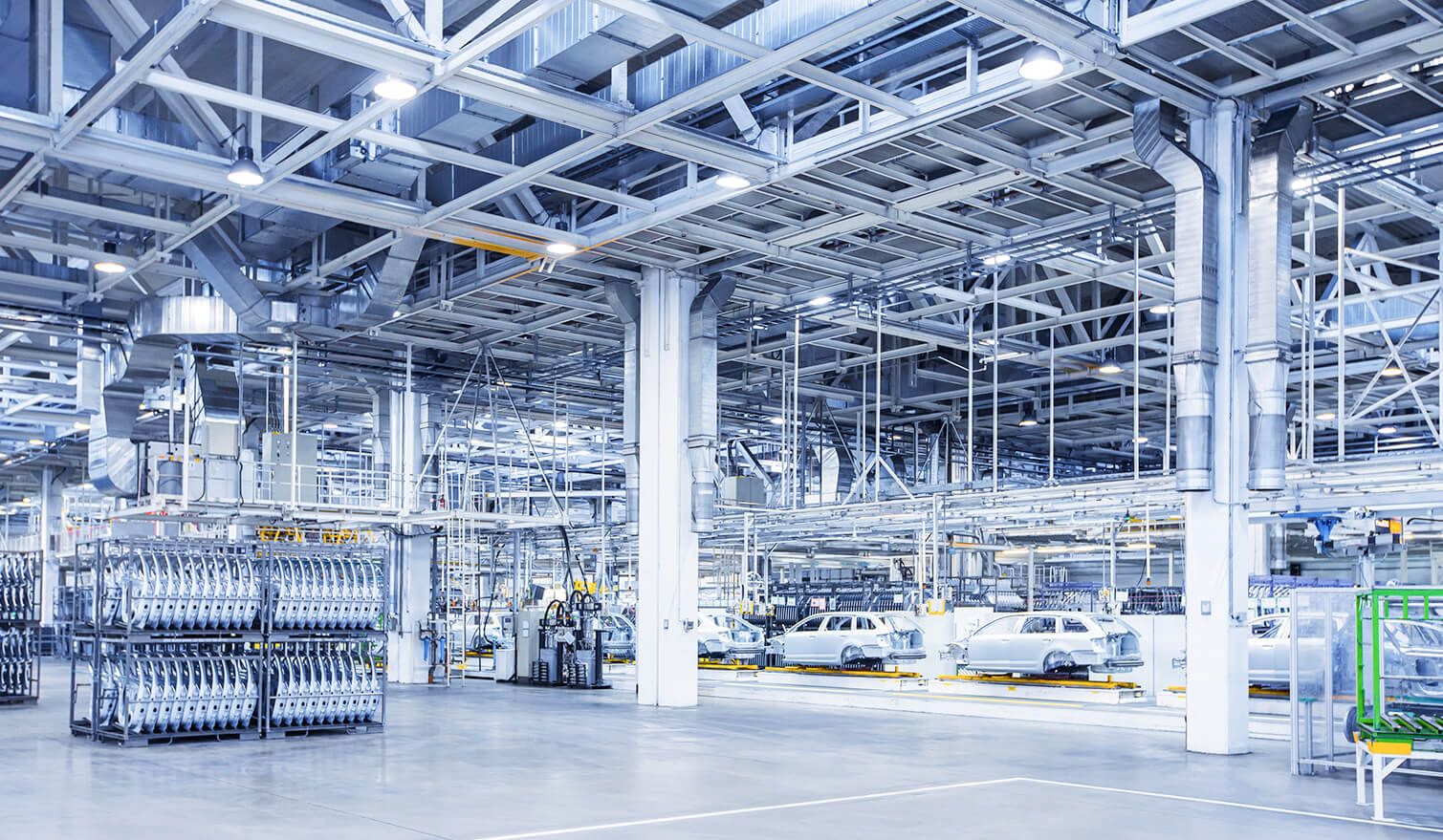 A large factory with numerous cars and lorries, showcasing modern lighting in the automotive production process