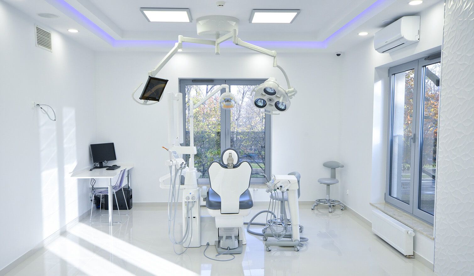 The interior of a dental surgery with a chair, computer and lamp, highlighting the importance of proper lighting in dentistry | Lumedic