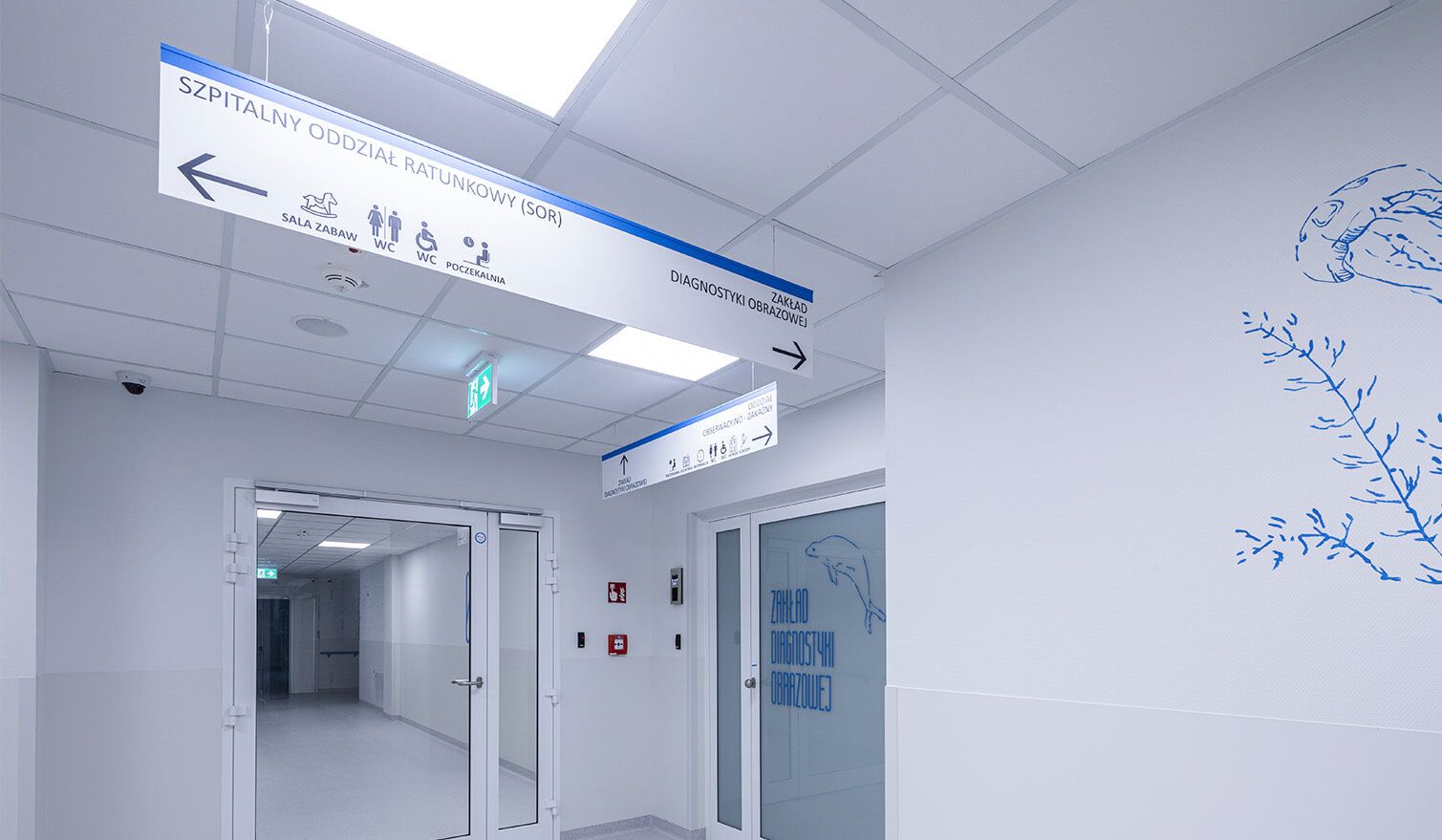 A corridor in a healthcare facility with clear signage on the walls to help patients and staff find their way around