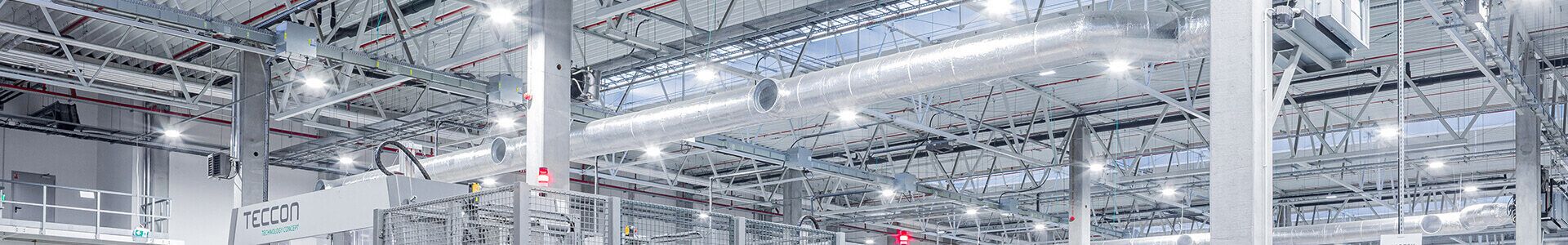 A large warehouse with metal shelving, lit by numerous lamps, providing good working conditions for the electronics industry