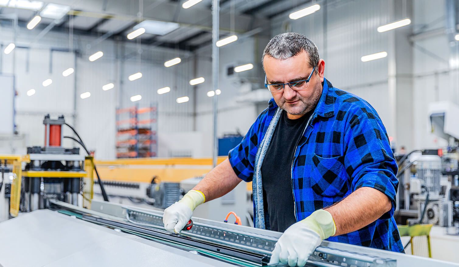 A man working at a machine in a factory, concentrating on the precise assembly of electronic components