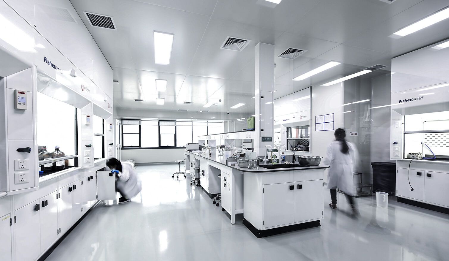 A pharmaceutical laboratory with white walls and cupboards, lit by bright light