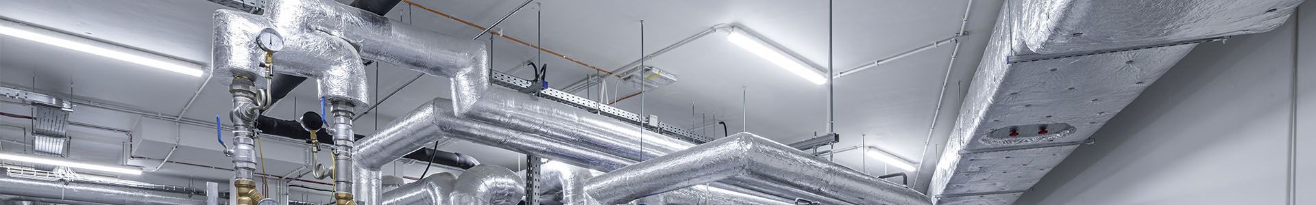 A spacious hall with numerous pipes and cables, illustrating a lighting system in the pharmaceutical industry