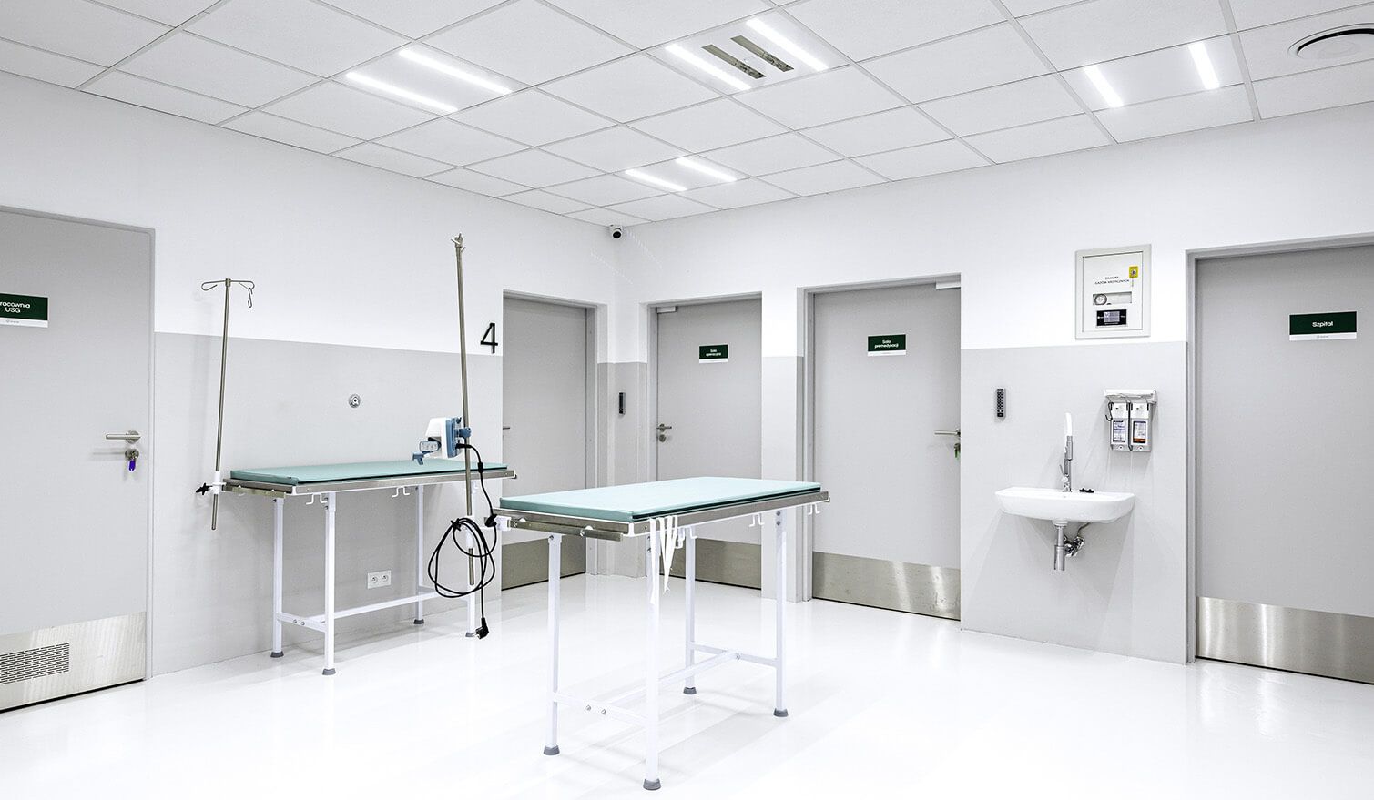 A room with two white doors and a table, ideal for use in a doctor’s surgery or treatment room | Lumedic