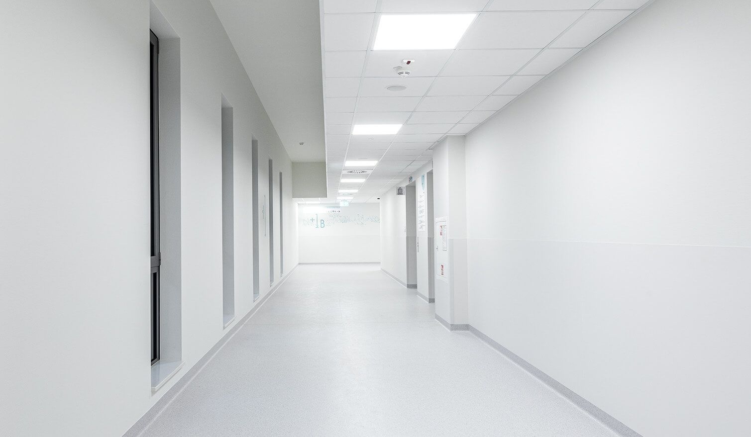 A long hospital corridor with white walls and bright lighting, ensuring comfort for patients and medical staff | Lumedic